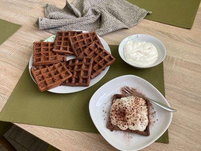 Kakaové vafle s tvarohovým krémem servírované na bílém talíři a zeleném prostírání