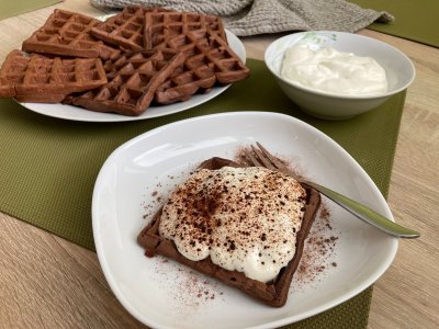 Kakaové vafle s tvarohovým krémem servírované na bílém talíři a zeleném prostírání