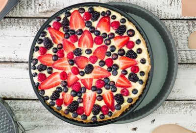 Koláčj z lesního ovoce v černé kulaté formě.