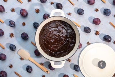 Povidla v bílém hrnci, kolem na stole švestky a badyán