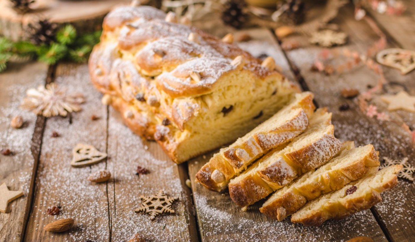 Nakrojená máslová vánočka s rozinkami a mandlemi, sypaná moučkovým cukrem.