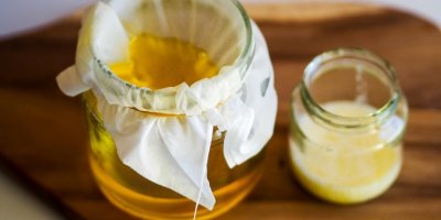 Přepuštěné máslo ghí ve sklenici, postavené na dřevěném stole.