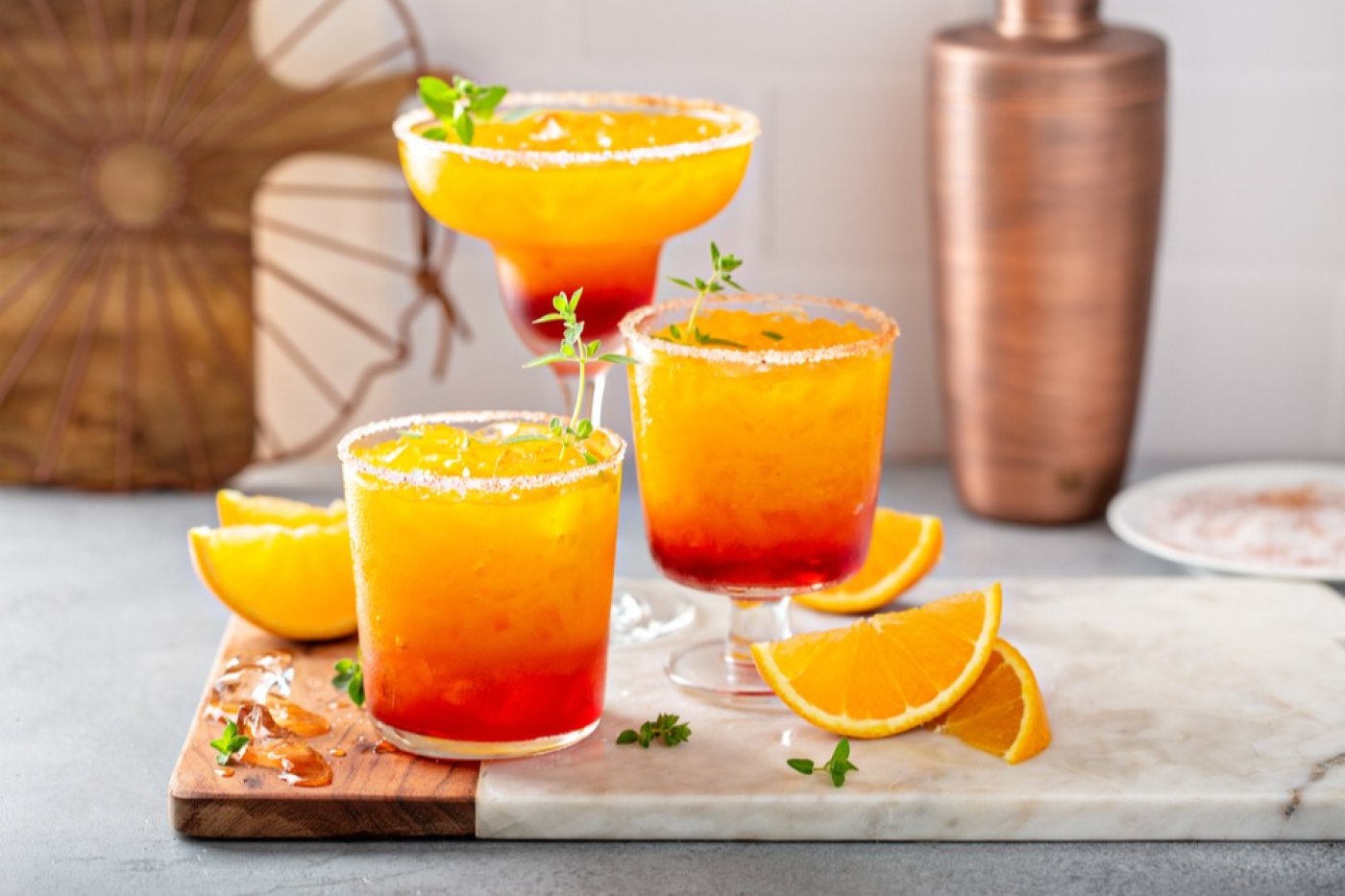 Tequila Sunrise v koktejlové sklenici, v pozadí další Tequila Sunrise ve sklenici na stopce