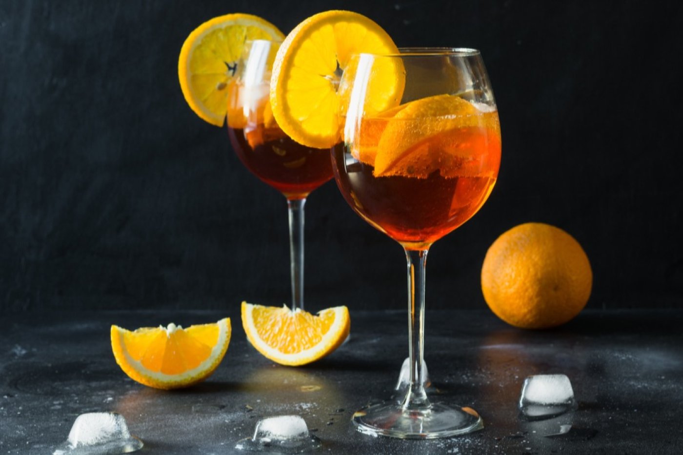 Aperol Spritz ve skleničkách postavených na dřevěném stole.