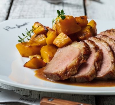 Kachní prsa na černém pivu s pečenou dýní, servírované na bílém talíři.