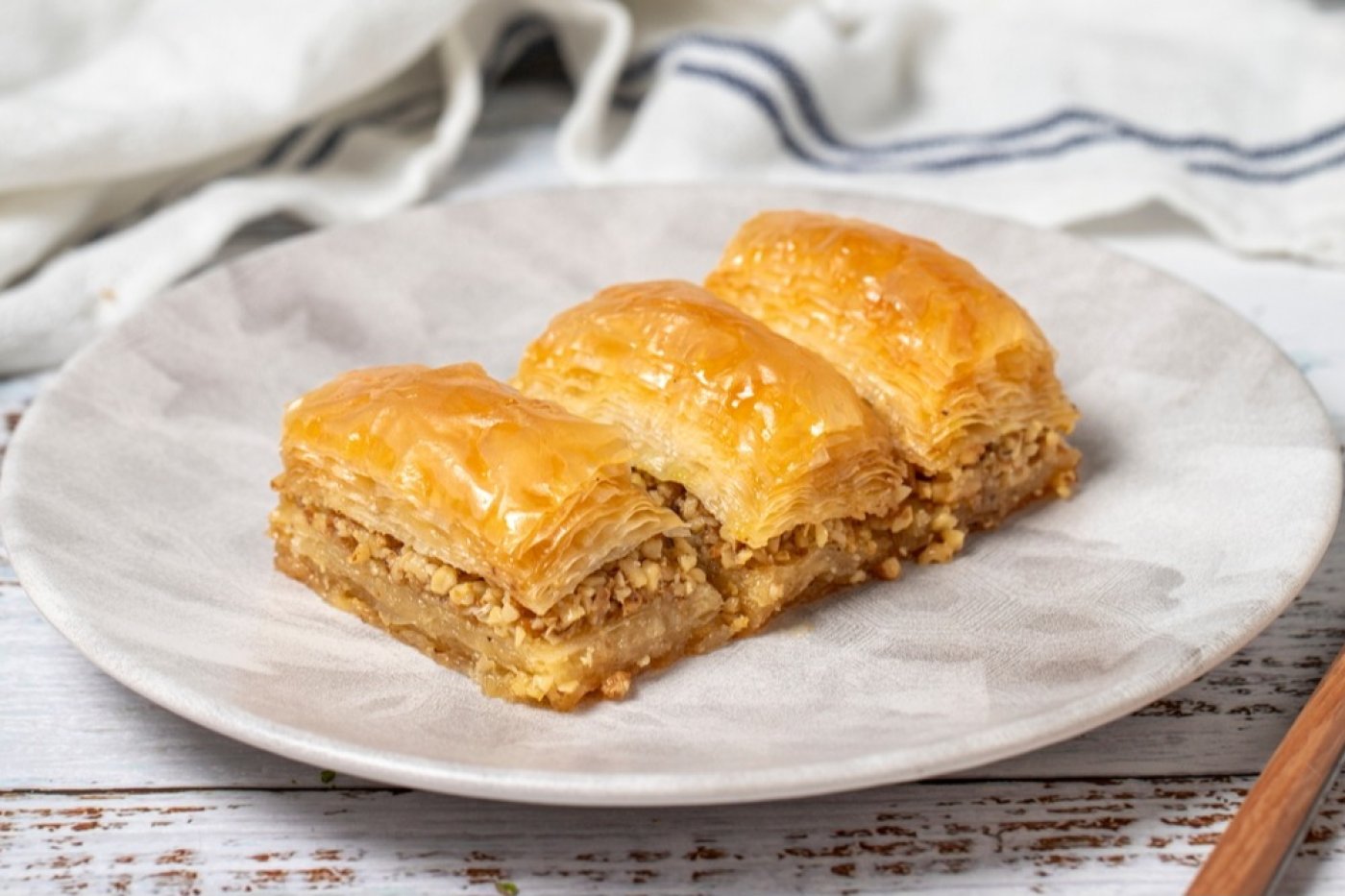 Baklava rozřezaná na obdélníky servírovaná na bílém talířku.