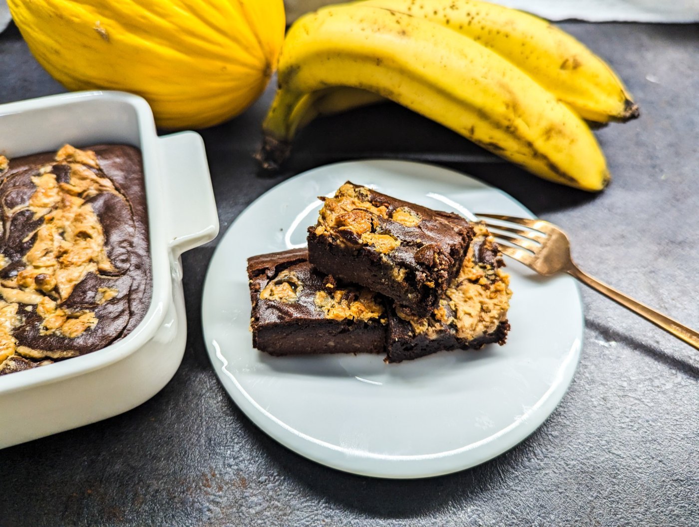 Brownies z arašídového másla na bílém dezertním talířku s vidličkou