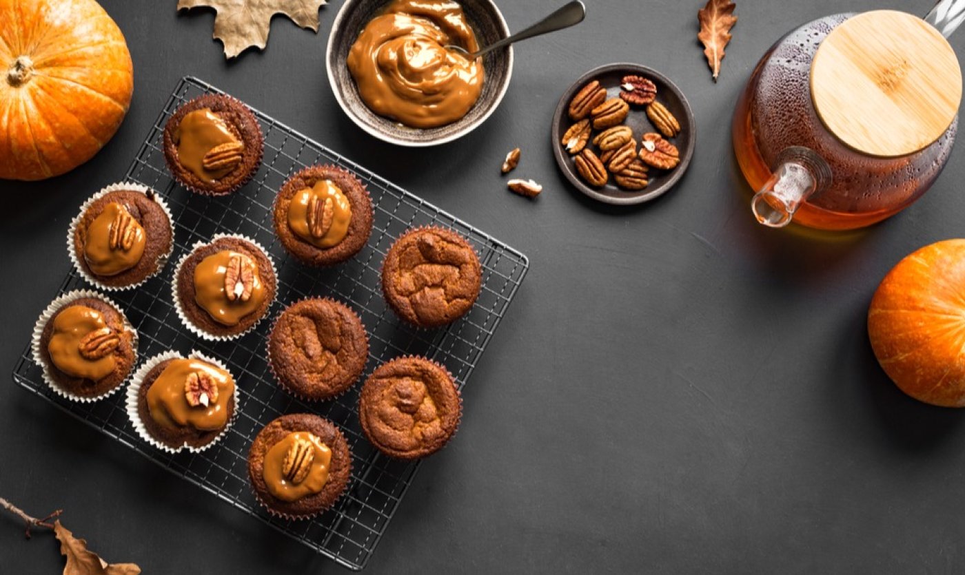 Dýňové latte muffiny s karamelem, ozdobené pekanovými ořechy, na černém podstavci