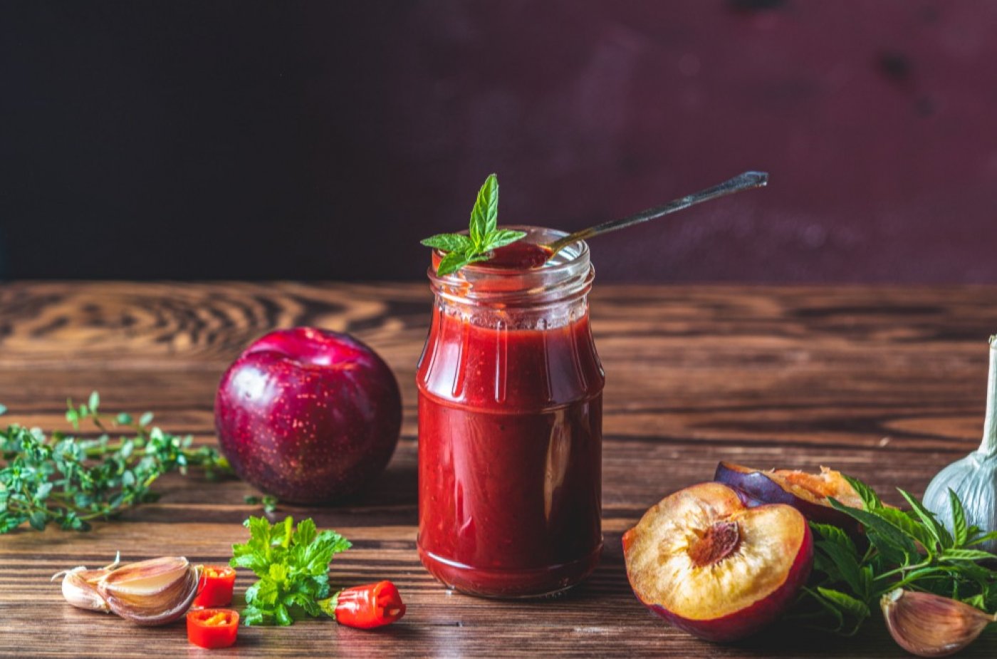 Švestkové chutney ve skleničce, ozdobené čerstvou mátou.