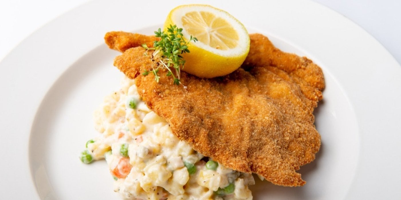 Smažený řízek s bramborovým salátem na bílém talíři