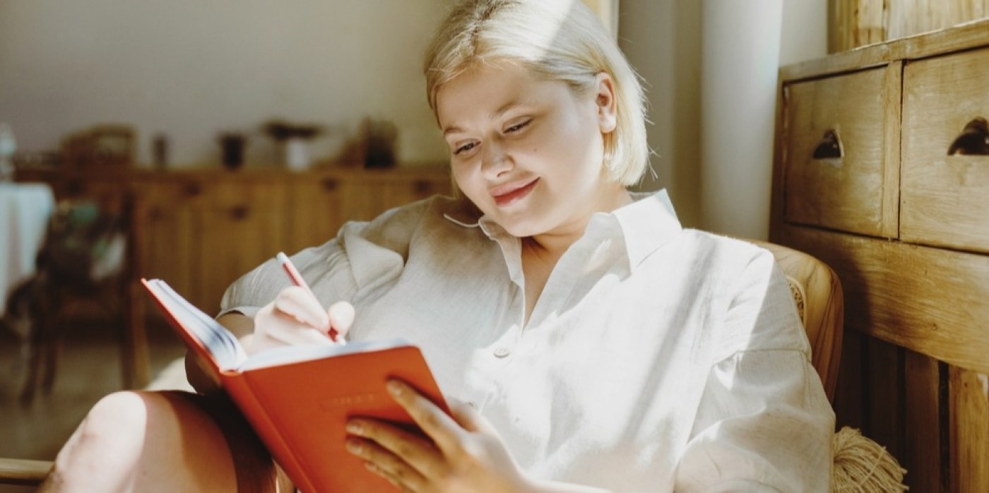 Žena píše do zápisníku a přemýšlí