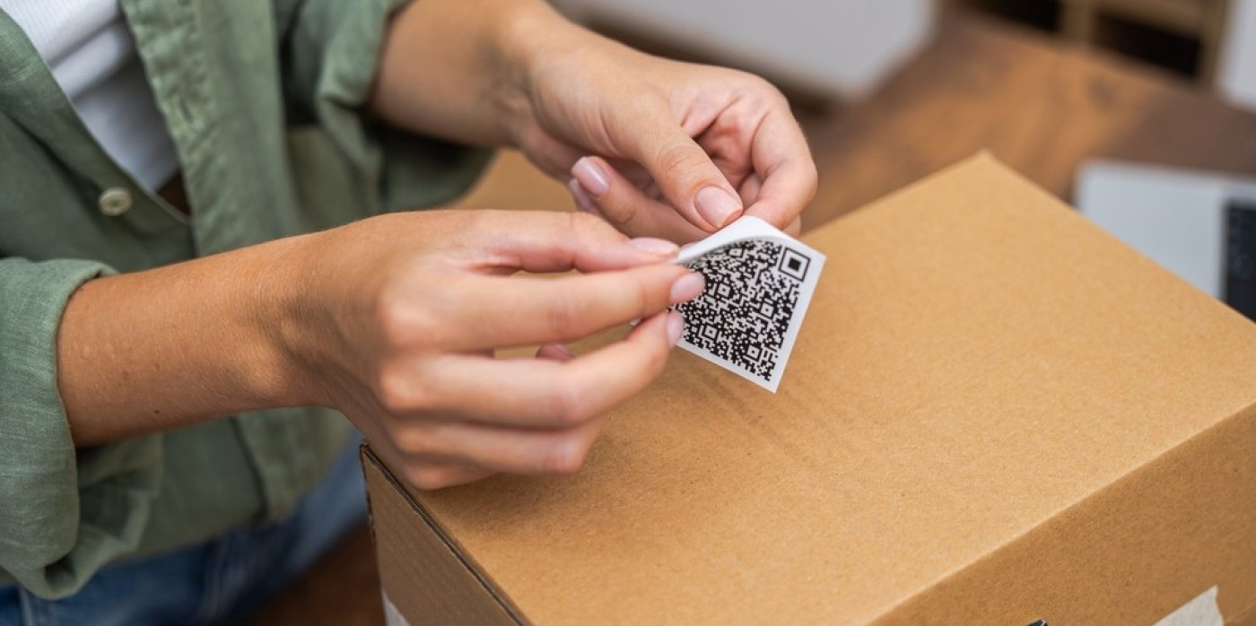 Ruce lepí QR kód na balík