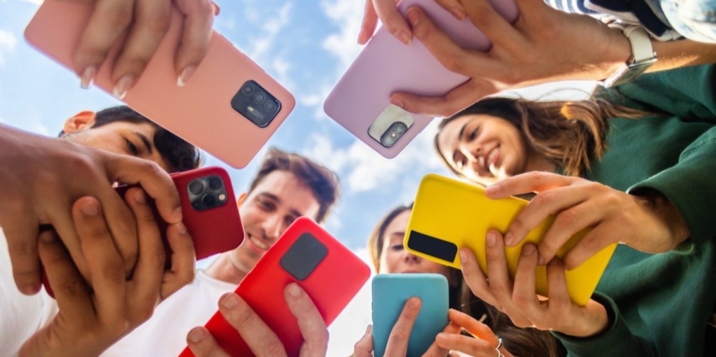 Mladí lidé stojí v kruhu a používají telefony