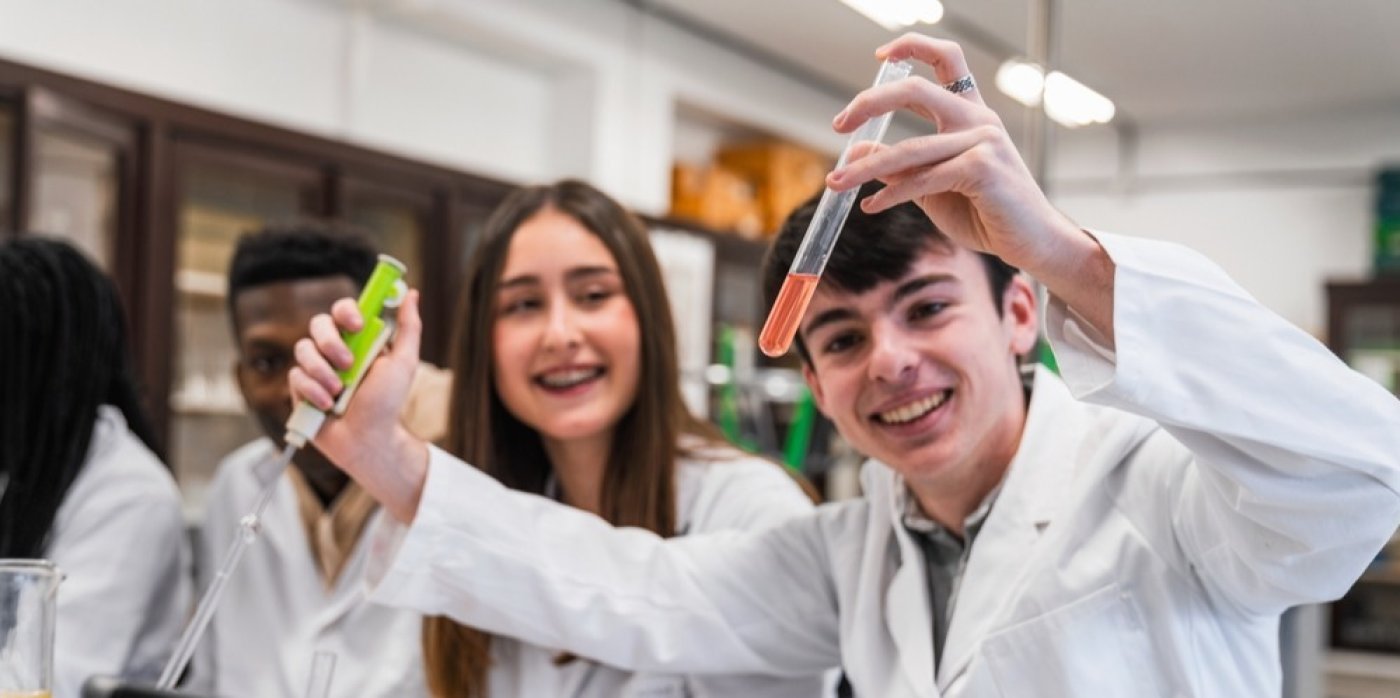 Mladí lidé ve třídě se dívají na zkumavky