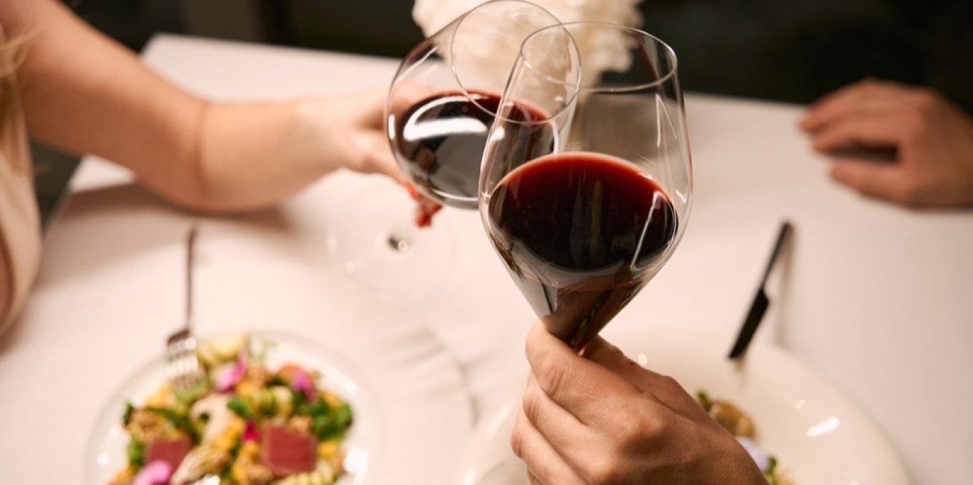 Lidé si připíjí červeným vínem