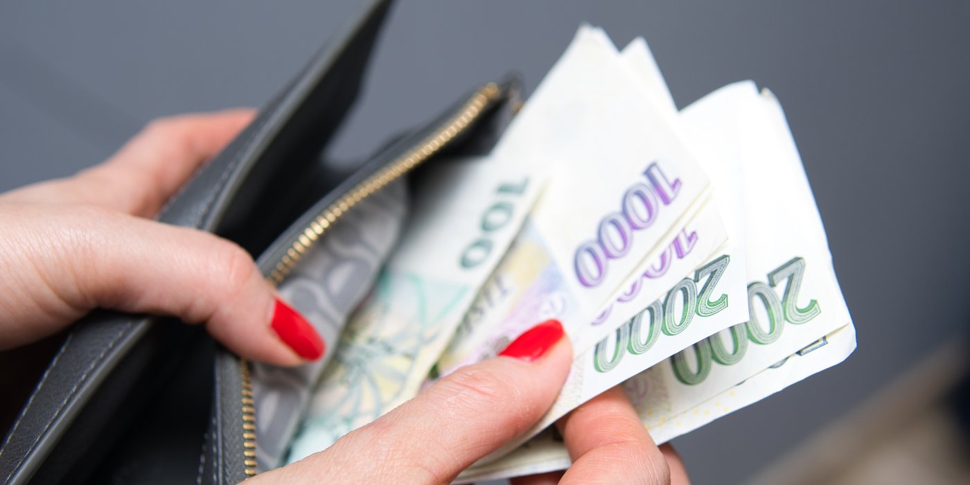 Žena vytahuje české bankovky z peněženky