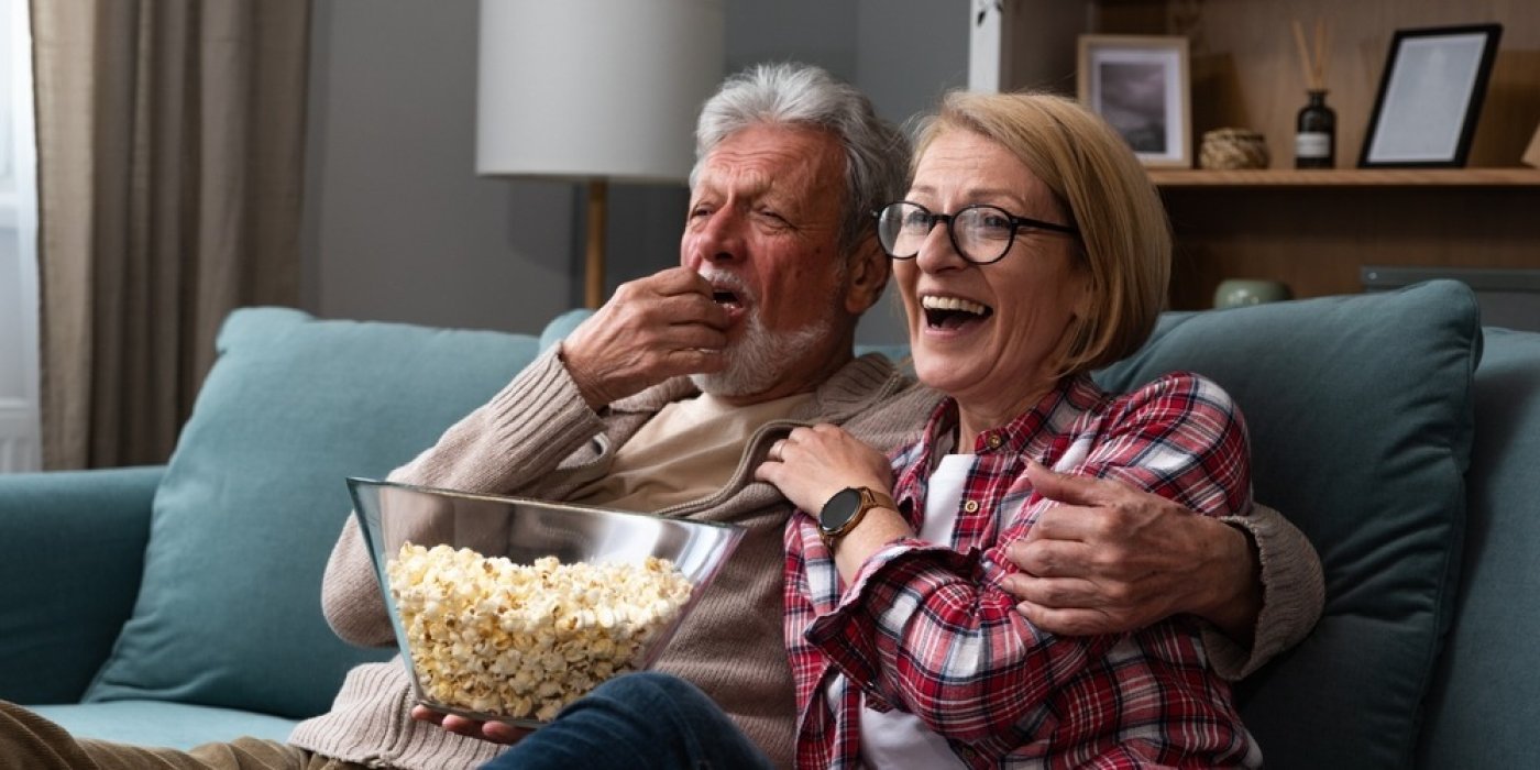 Starší pár se směje a jí popcorn