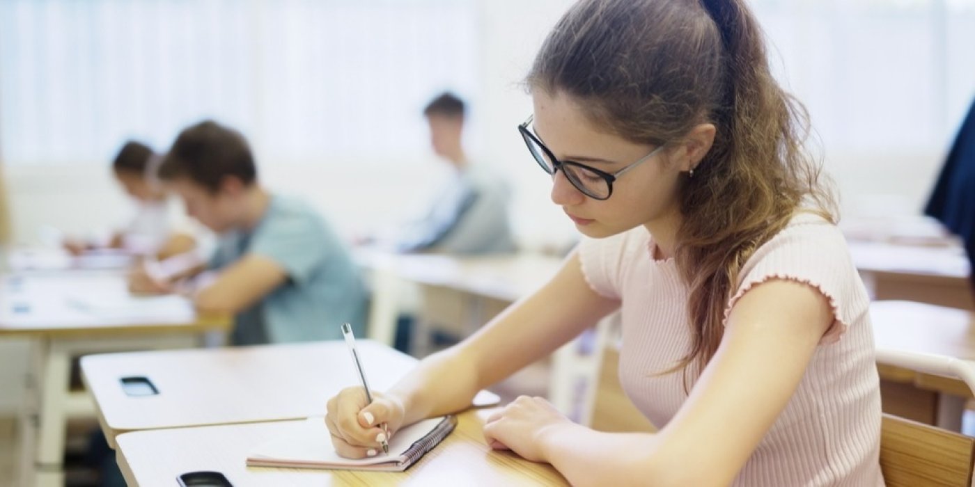 Teenagerka píše ve škole do sešitu