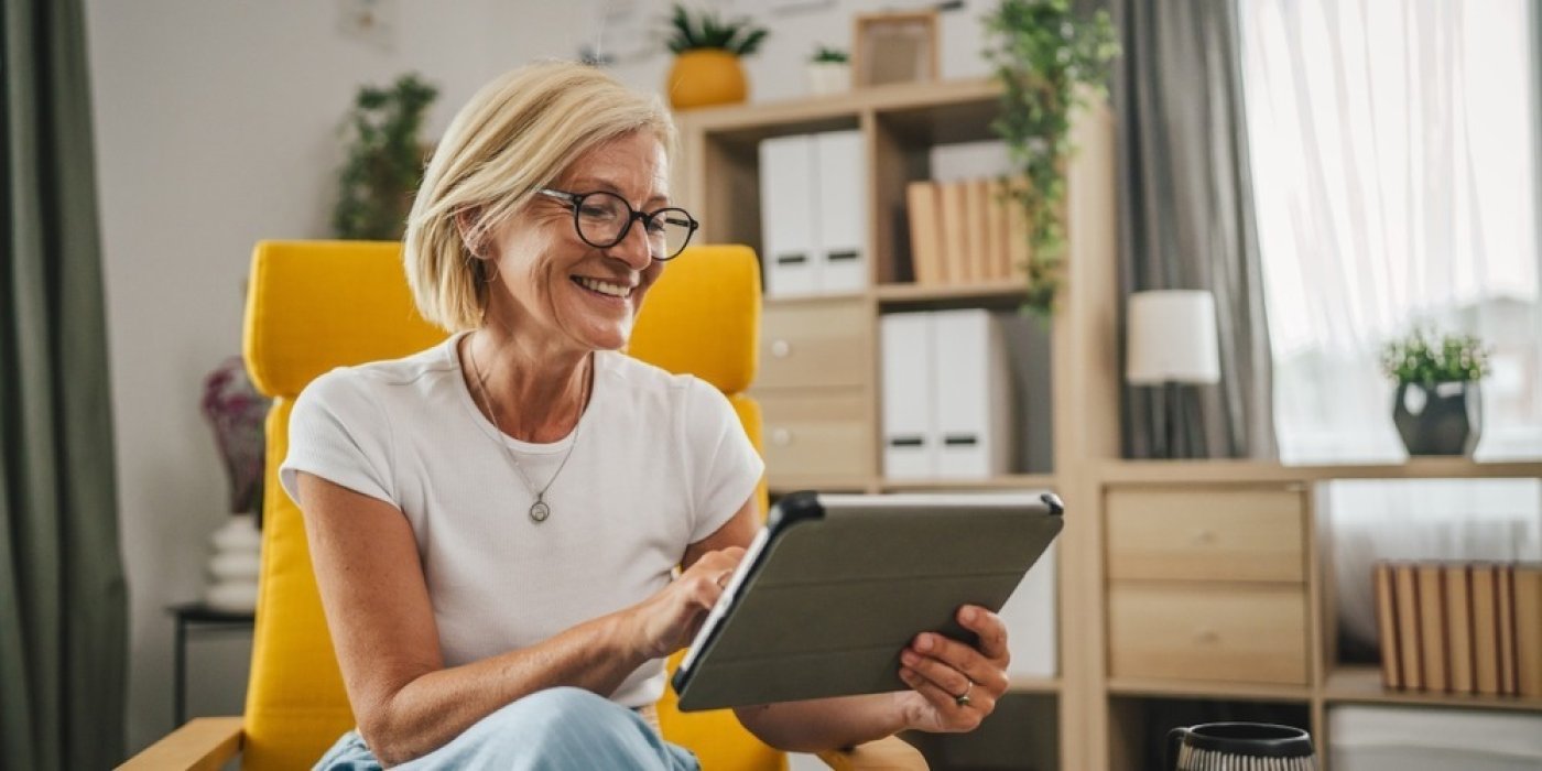 Starší žena se směje při čtení z tabletu