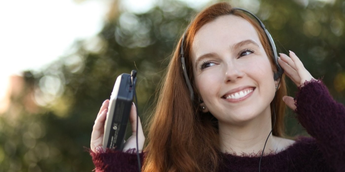 Žena poslouchá hudbu přes sluchátka z walkmanu
