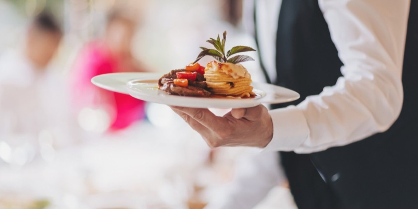 Číšník nese talíř s jídlem