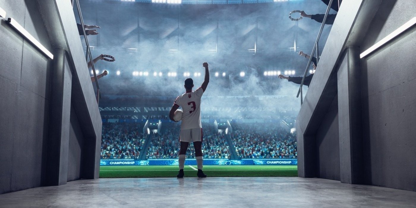 Hráč fotbalu s míčem na plném stadionu