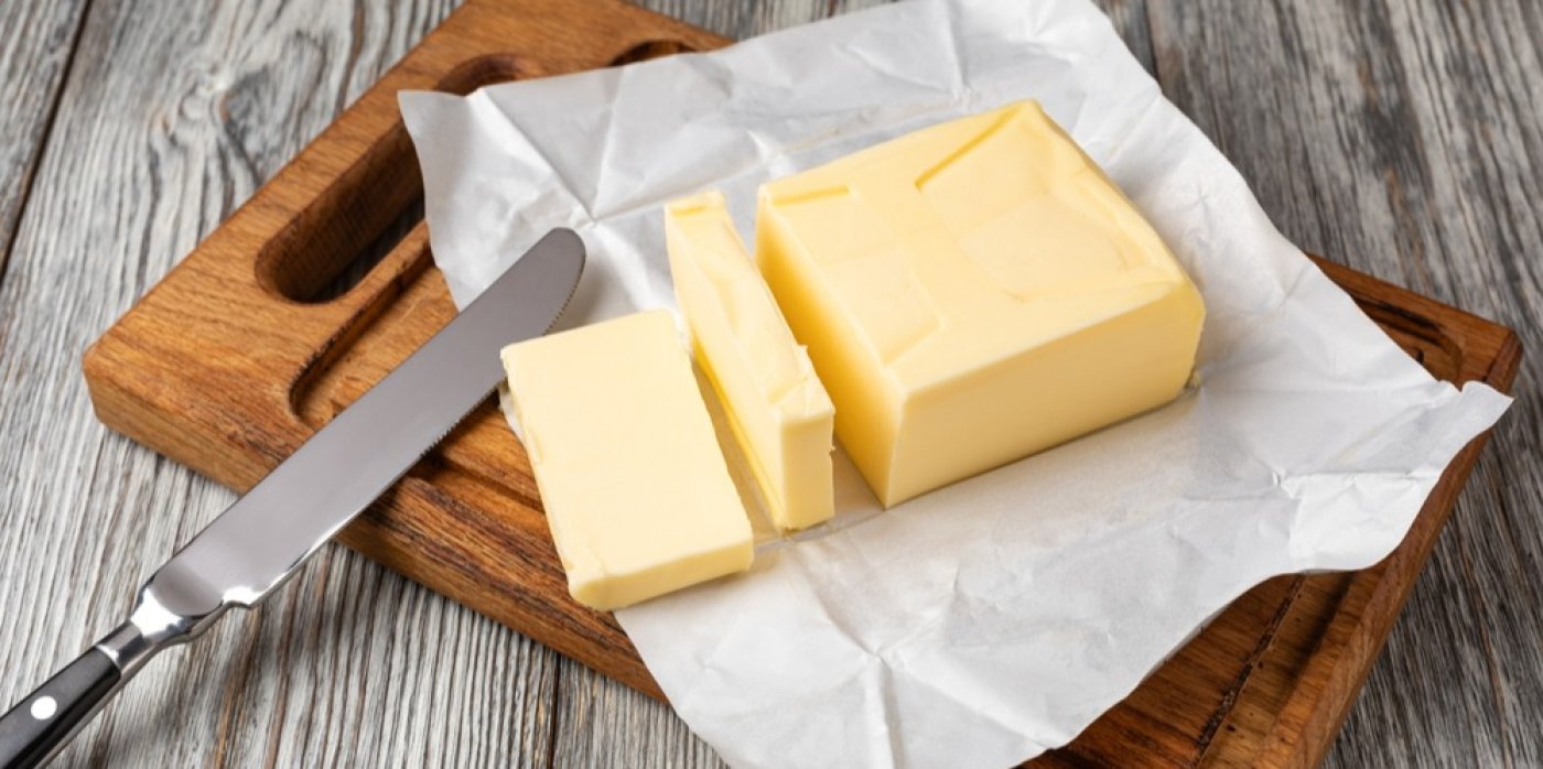 Nakrájené máslo na obalu a dřevěném prkénku